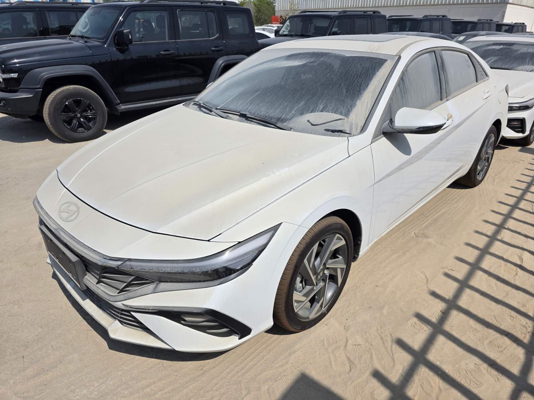 White Hyundai Elantra sedan viewed from the front three-quarter angle in an outdoor vehicle yard