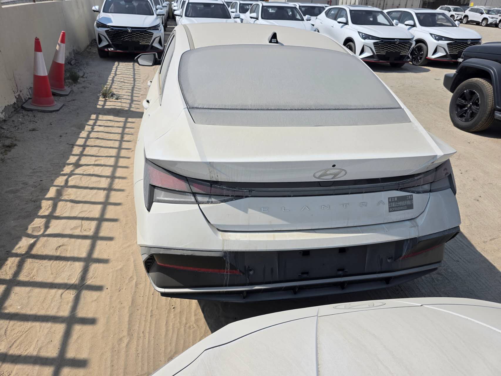 Rear view of a white Hyundai Elantra sedan with a full-width rear lamp assembly