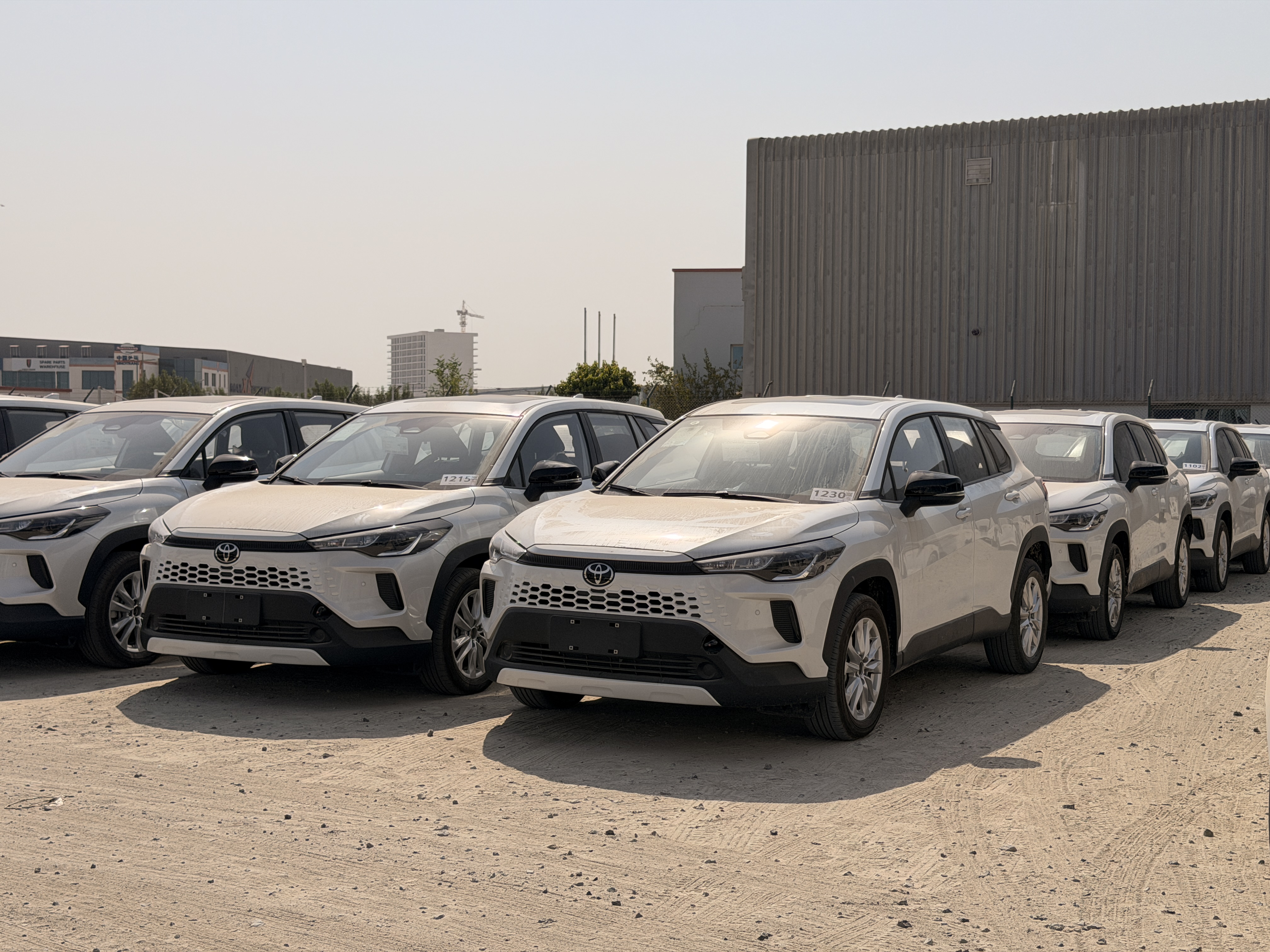 White Toyota Corolla Cross SUVs parked in a row in an outdoor vehicle yard