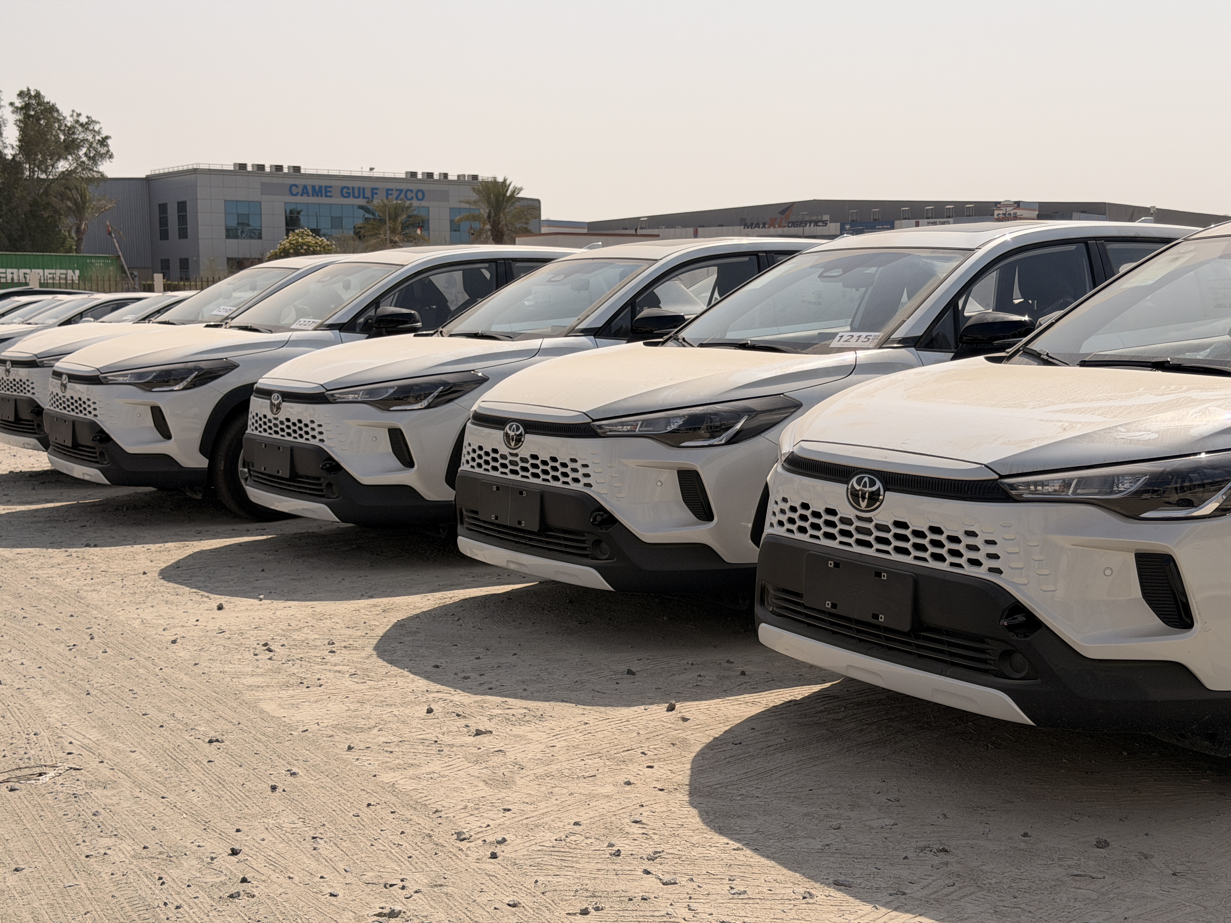 Front views of white Toyota Corolla Cross SUVs lined up in an outdoor vehicle yard