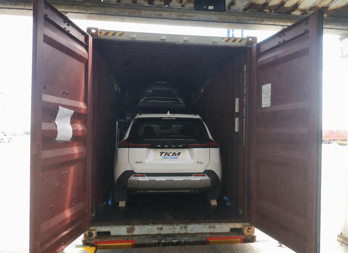 White Toyota RAV4 positioned inside an open shipping container